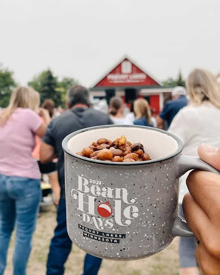 Photo of person holding a mug of beans in the crowd at Bean Hole Days