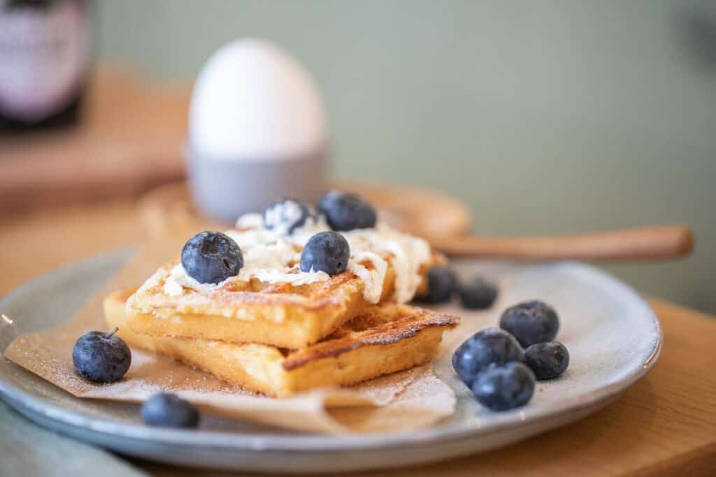 1920x1280 photo of waffles topped with whipped cream and blueberries