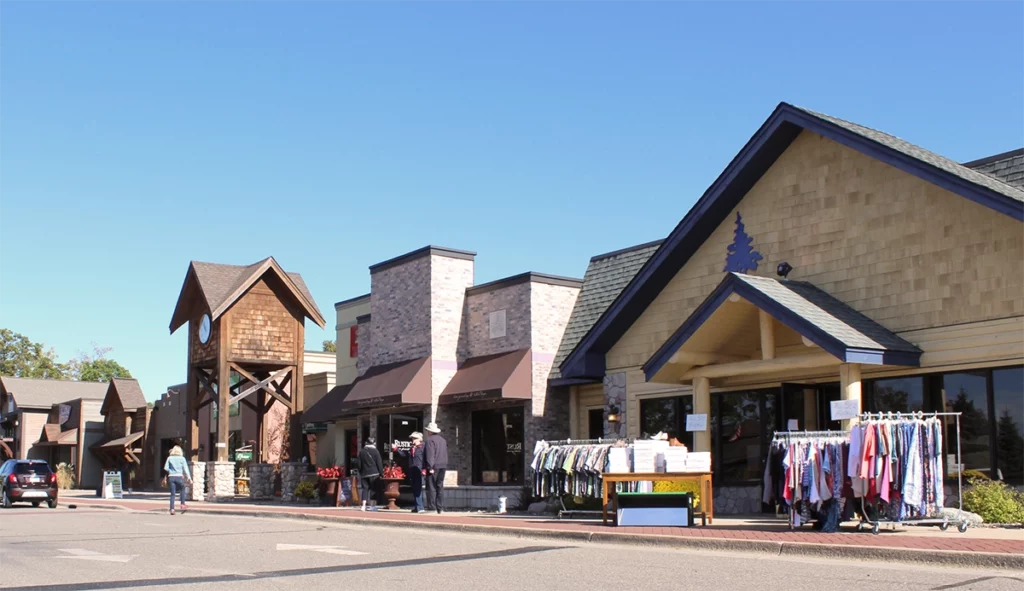 Image of Crosslake Town Square showing a street of shops and people shopping on a sunny summer day