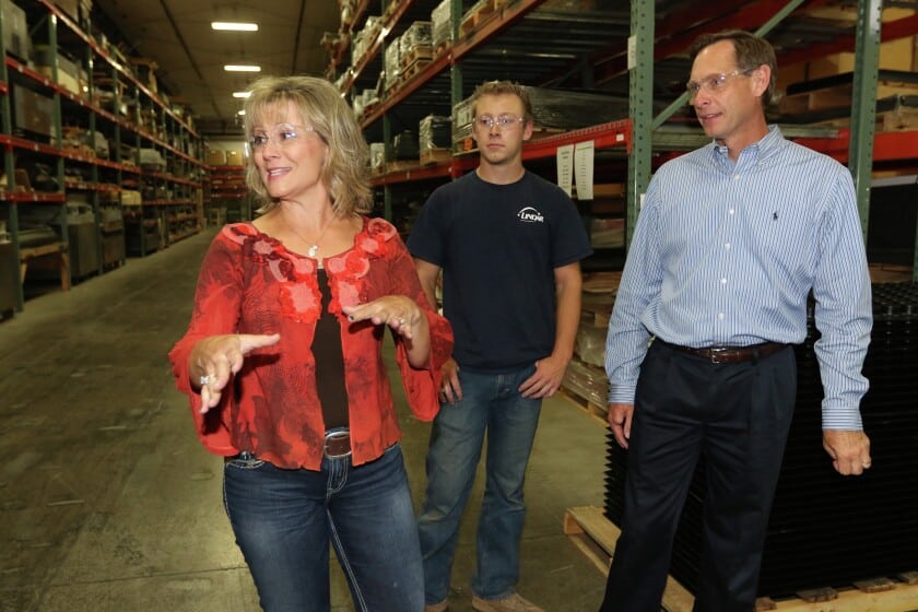 Photo of a blone woman and two men at Lindar manufacturing building giving a tour