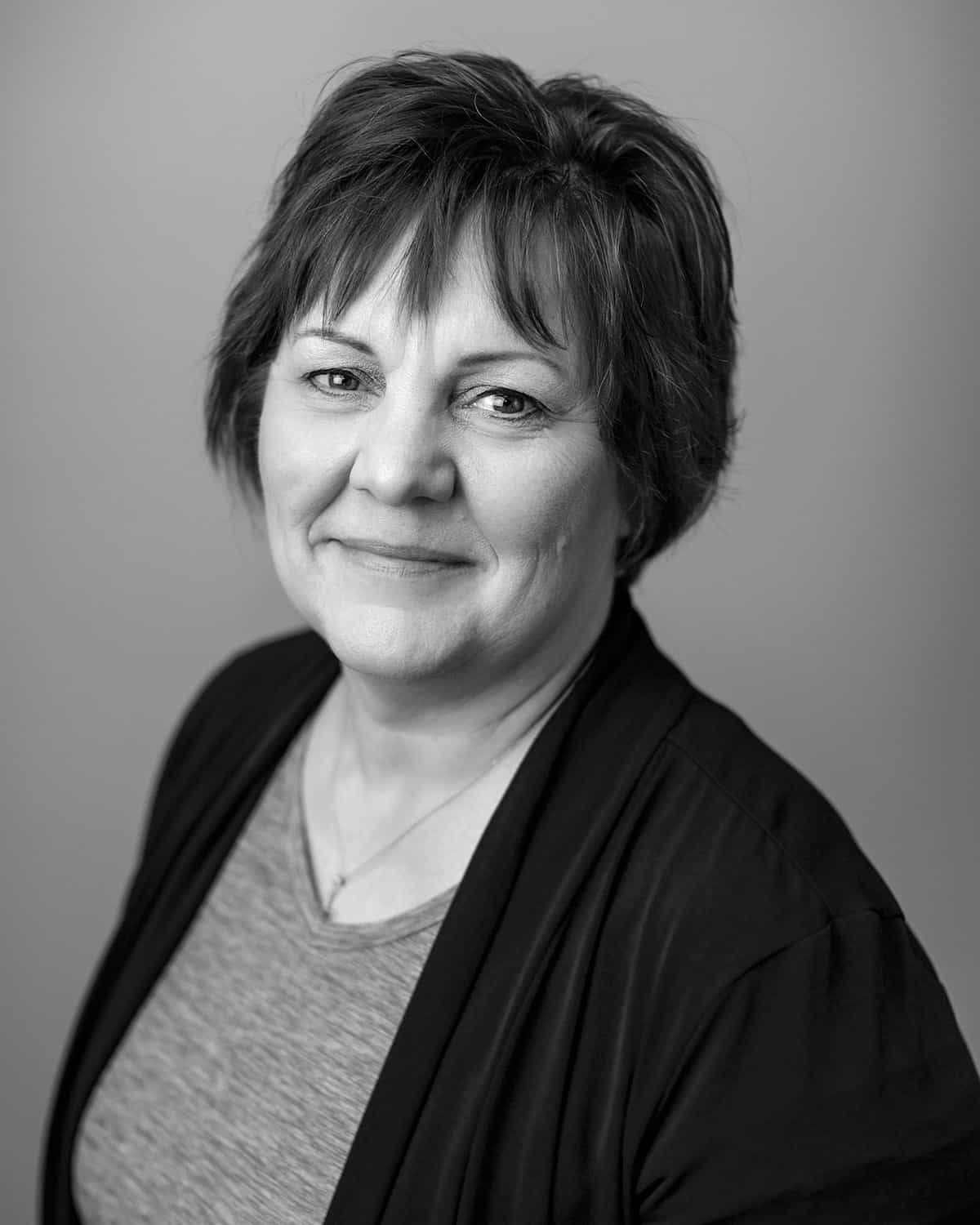 Black and white headshot of Lori Davies, a middle aged woman smiling