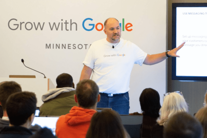 Photo of middle aged man Dave Meyer presenting in the front of a room to a large class with Google logo in the background
